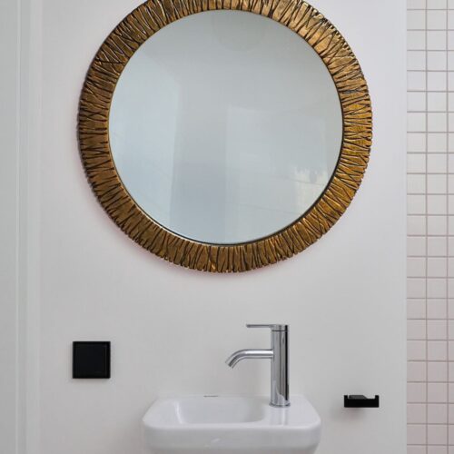 Круглое зеркало в раме латунь на стене в ванной комнате