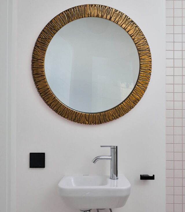 Круглое зеркало в раме латунь на стене в ванной комнате