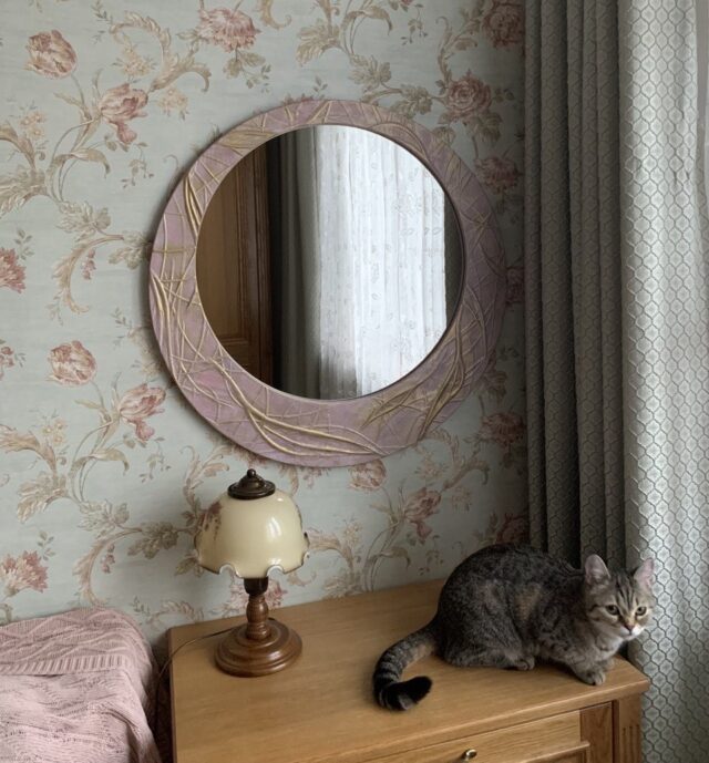Интерьер спальни с круглым зеркалом в розовой раме